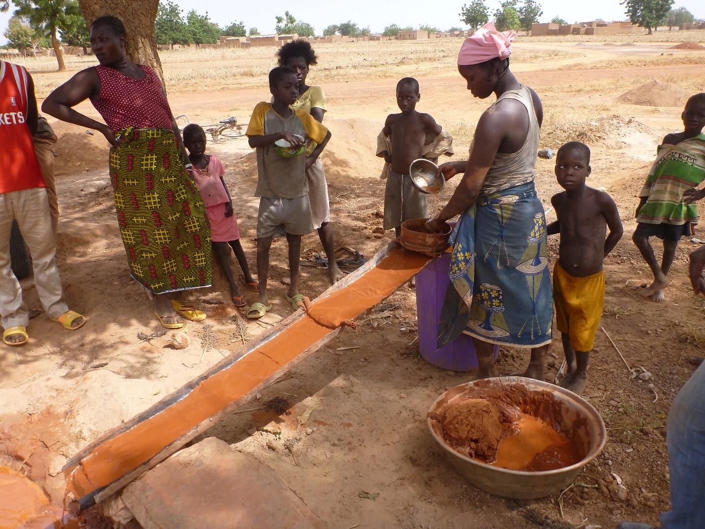 A woman miner performing sluice washing while taking care of young children (Photo credit: Dr. kevin Telmer, Artisanal Gold Council)
