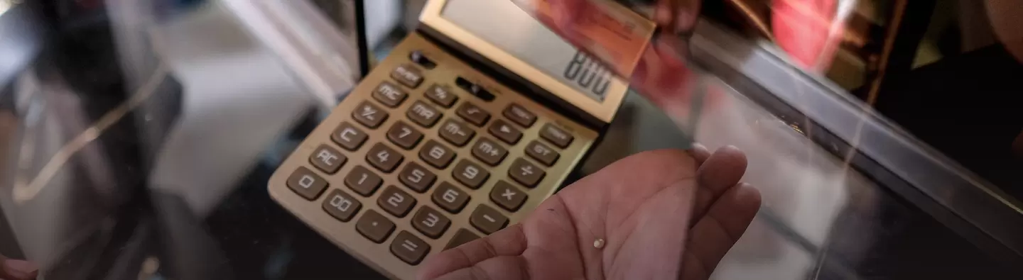 Hand with small gold nugget and calculator