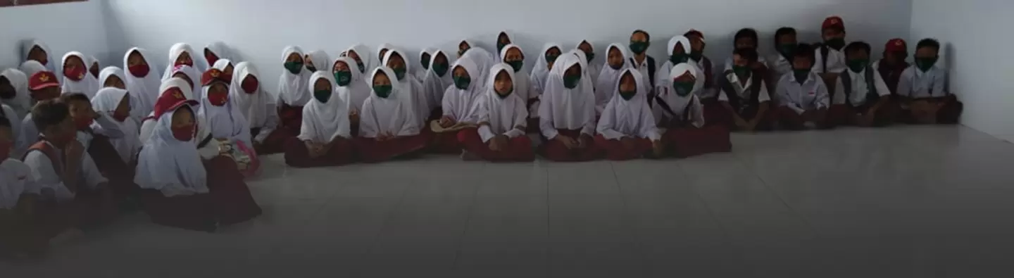 A group of children in Indonesia sit on the floor for a storytelling exercise about the dangers of mercury