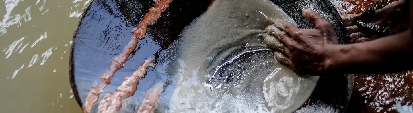 Miner in the Philippines panning for gold using mercury