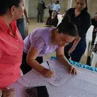Mujer de la cooperativa firmando la personería jurídica