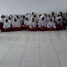 A group of children in Indonesia sit on the floor for a storytelling exercise about the dangers of mercury