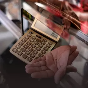 Hand with small gold nugget and calculator
