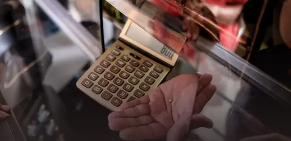 Hand with small gold nugget and calculator