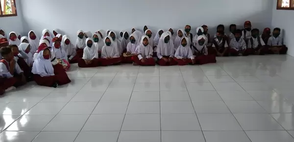A group of children in Indonesia sit on the floor for a storytelling exercise about the dangers of mercury